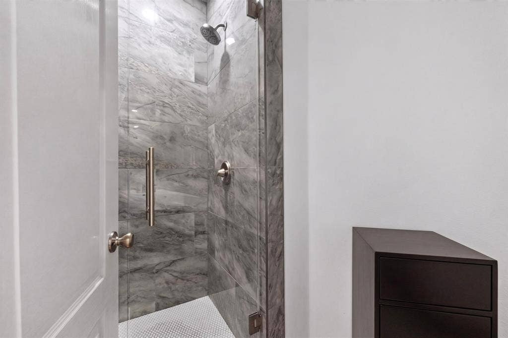 713 Mockingbird Court, Crowley, TX 76036 Tiled walk-in shower with a glass enclosure, rainfall showerhead, and circular floor tile