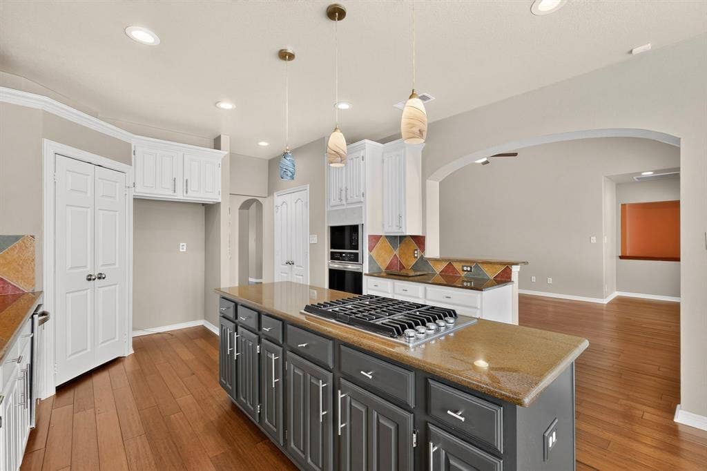 713 Mockingbird Court, Crowley, TX 76036 Kitchen featuring a gas cooktop on a central island, recessed lighting, wood-finish flooring, and arched doorways