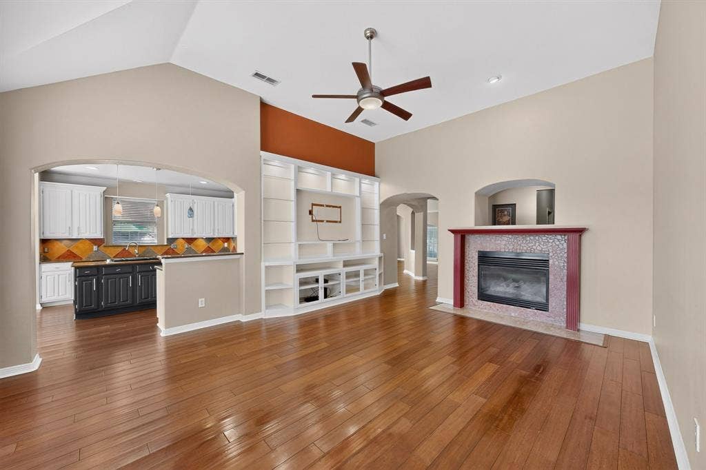 713 Mockingbird Court, Crowley, TX 76036 Wood-finish flooring, vaulted ceiling, built-in entertainment center, fireplace with tiled surround, and recessed lighting