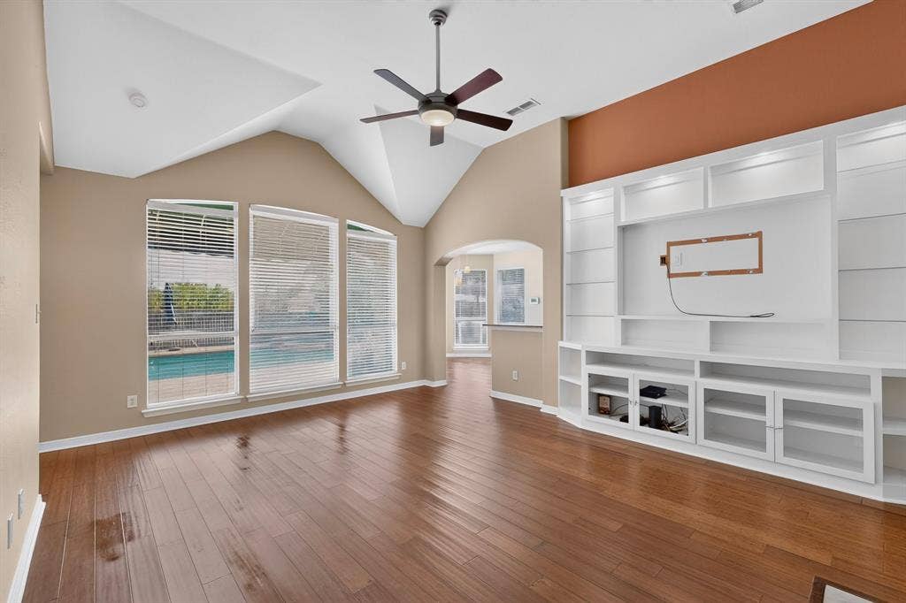 713 Mockingbird Court, Crowley, TX 76036 Vaulted ceilings, wood-finish flooring, custom built-in entertainment center, ceiling fan, and multiple windows overlooking a pool