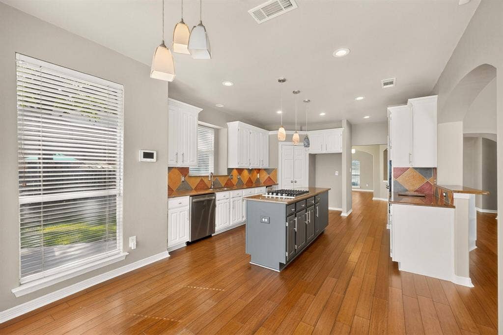 713 Mockingbird Court, Crowley, TX 76036 Kitchen featuring wood-finish flooring, white cabinetry, a center island with cooktop, stainless steel dishwasher, and recessed lighting