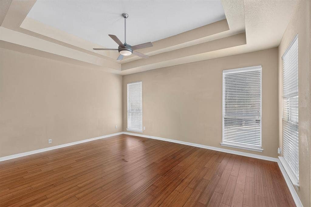 713 Mockingbird Court, Crowley, TX 76036 Tray ceiling with a ceiling fan, wood-finish flooring, and multiple windows with blinds