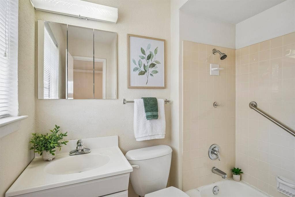 902 N Lindale Lane, Richardson, TX 75080 A quaint ensuite bathroom welcomes you with vintage shower tile and soft color tones.