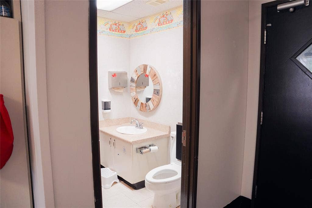 2705 Virginia Parkway, McKinney, TX 75071 Compact bathroom featuring a white porcelain toilet, vanity sink with cabinet storage, and decorative wall clock
