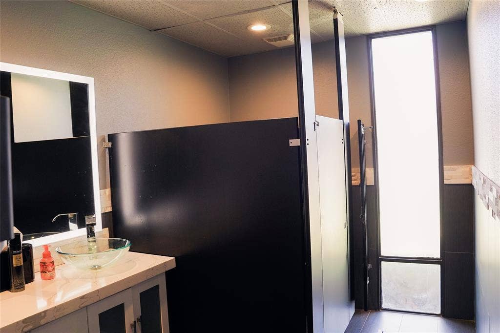2705 Virginia Parkway, McKinney, TX 75071 Restroom with privacy partitions, a vanity featuring a vessel sink, and an exterior window