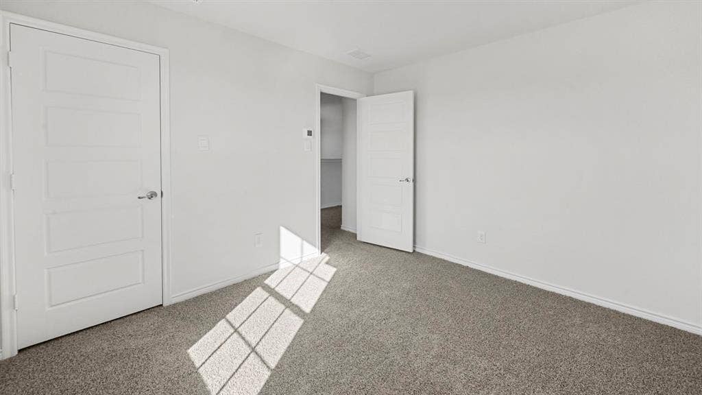 8425 Everly Drive, Garland, TX 75043 Carpeted room with a five-panel interior door and a second open doorway revealing an interior space