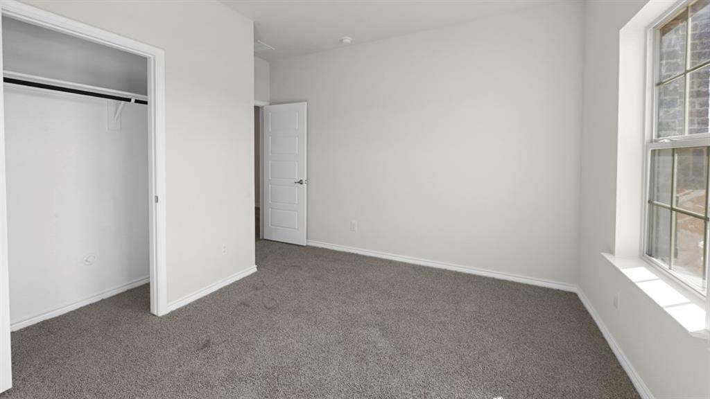 8425 Everly Drive, Garland, TX 75043 Carpeted room featuring a double-hung window, a built-in closet with a hanging rod, and a paneled interior door