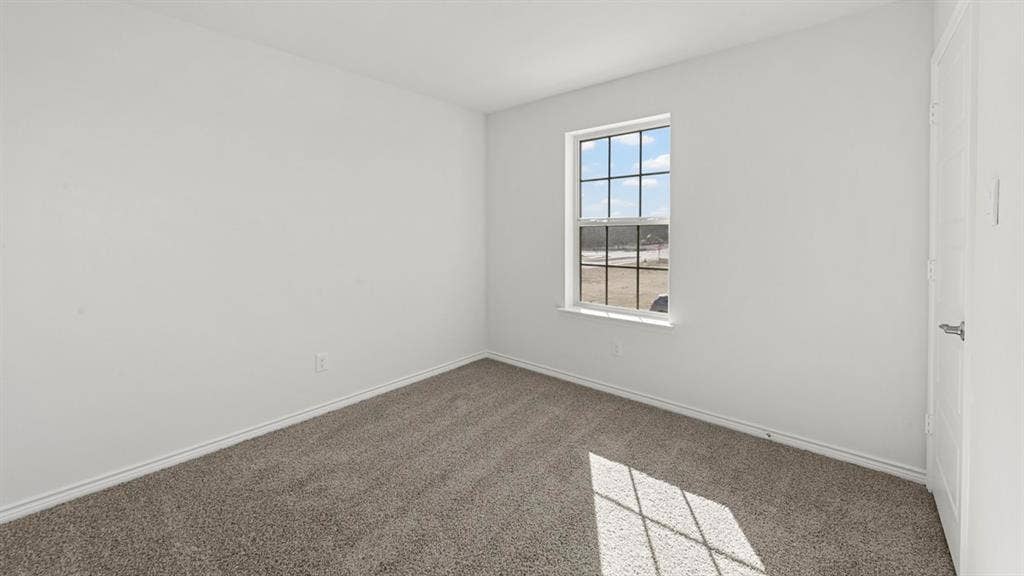 8425 Everly Drive, Garland, TX 75043 Carpeted room with a multi-pane window and a white door featuring a chrome handle