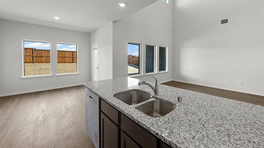 8425 Everly Drive, Garland, TX 75043 Kitchen island featuring a dual stainless steel sink and light granite countertop
