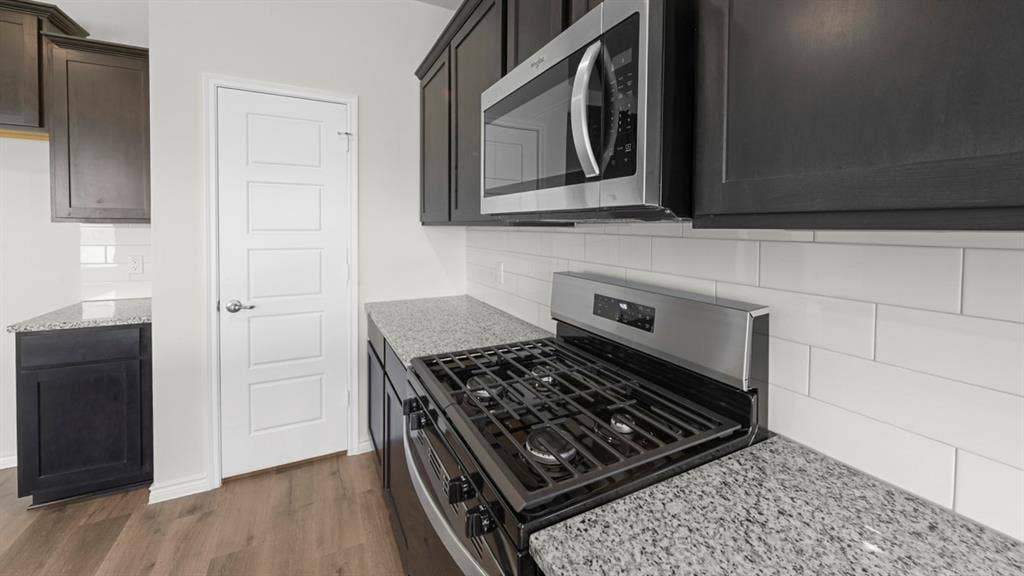 8425 Everly Drive, Garland, TX 75043 Modern kitchen featuring stainless steel gas cooktop with multiple burners, integrated microwave above the range, and granite-style countertops