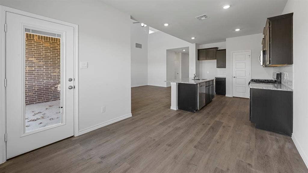 8425 Everly Drive, Garland, TX 75043 Open-concept kitchen with dark cabinetry, granite-style countertops, and a subway tile backsplash