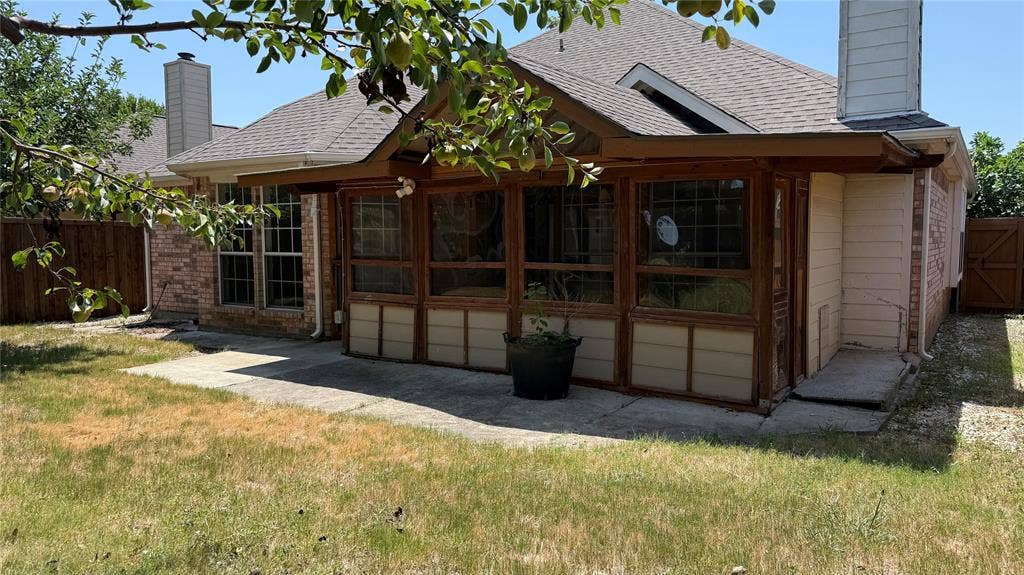 3312 Woodberry Lane, McKinney, TX 75071 Expansive outdoor space featuring a covered patio, a sunroom with wood-frame windows, and a brick exterior