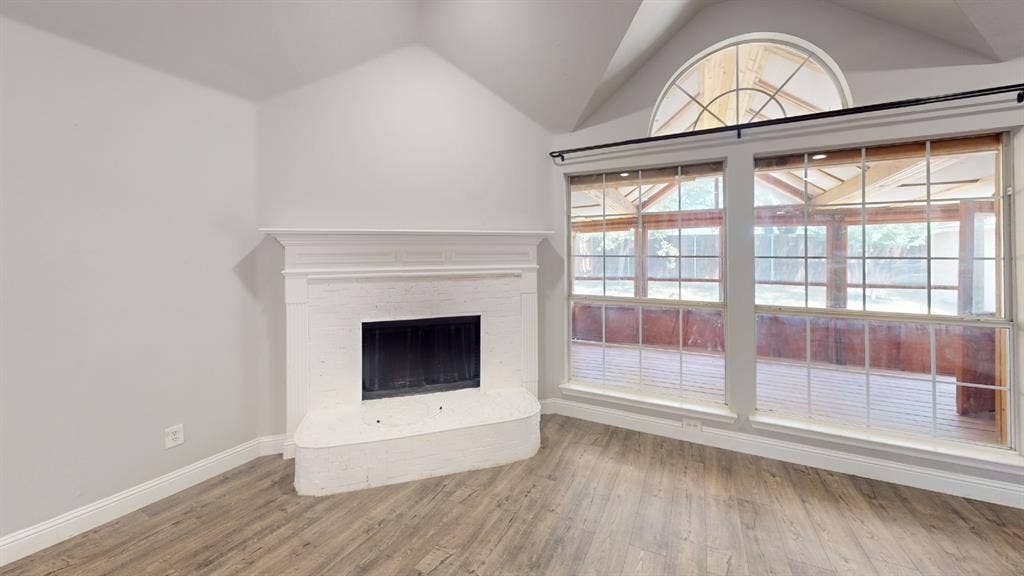 3312 Woodberry Lane, McKinney, TX 75071 Living area featuring a painted brick fireplace with a mantel, vaulted ceiling, and wood-finish flooring