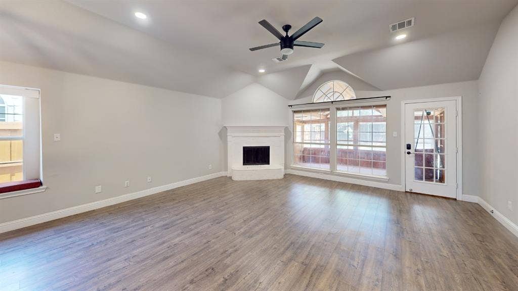 3312 Woodberry Lane, McKinney, TX 75071 Spacious open-concept great room showcasing gleaming wood-finish flooring, vaulted ceiling with architectural detail, and a modern ceiling fan