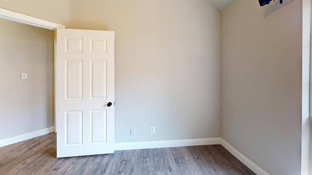 3312 Woodberry Lane, McKinney, TX 75071 Bright secondary bedroom featuring neutral wall finishes, wood-finish flooring throughout, and a six-panel closet door with polished hardware