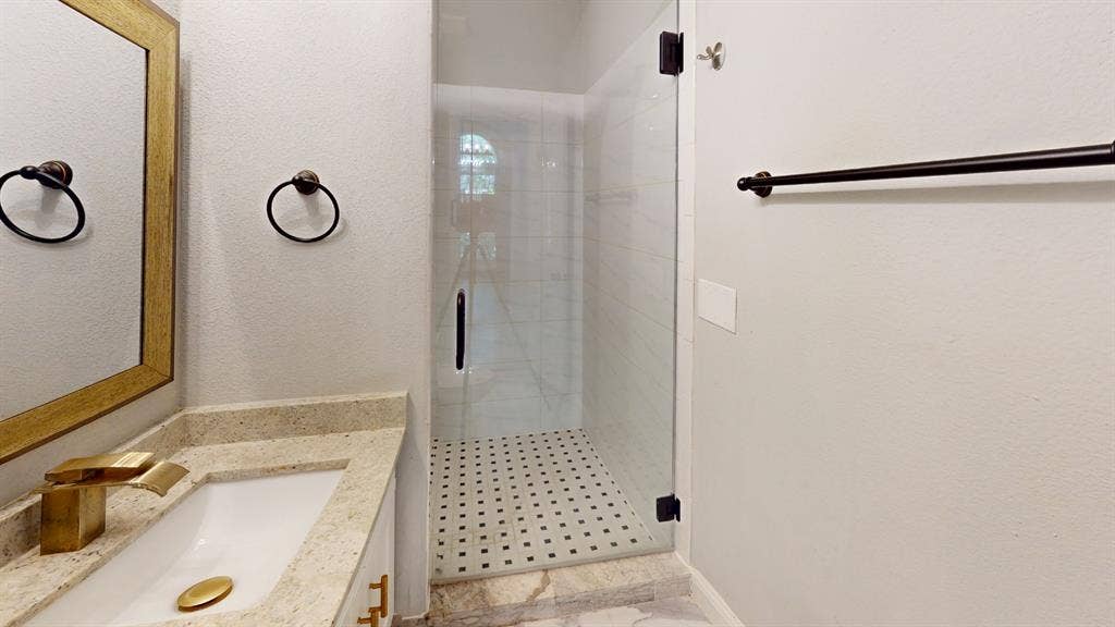 3312 Woodberry Lane, McKinney, TX 75071 Modern bathroom featuring a walk-in shower with clear glass enclosure, white subway tile walls, and a black and white mosaic tile floor