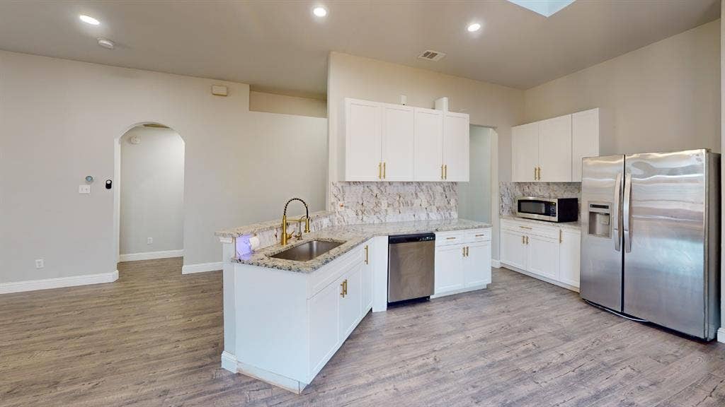 3312 Woodberry Lane, McKinney, TX 75071 Modern kitchen featuring white cabinetry, gold-tone hardware, and a stone-finish backsplash