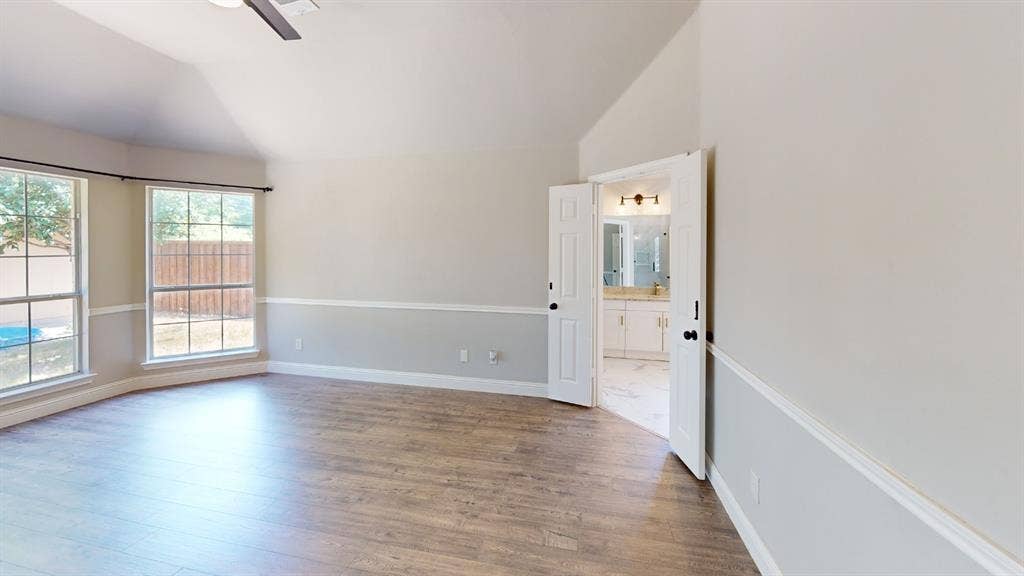 3312 Woodberry Lane, McKinney, TX 75071 Spacious room featuring vaulted ceilings, wood-finish flooring, and abundant natural light from dual glass doors and windows