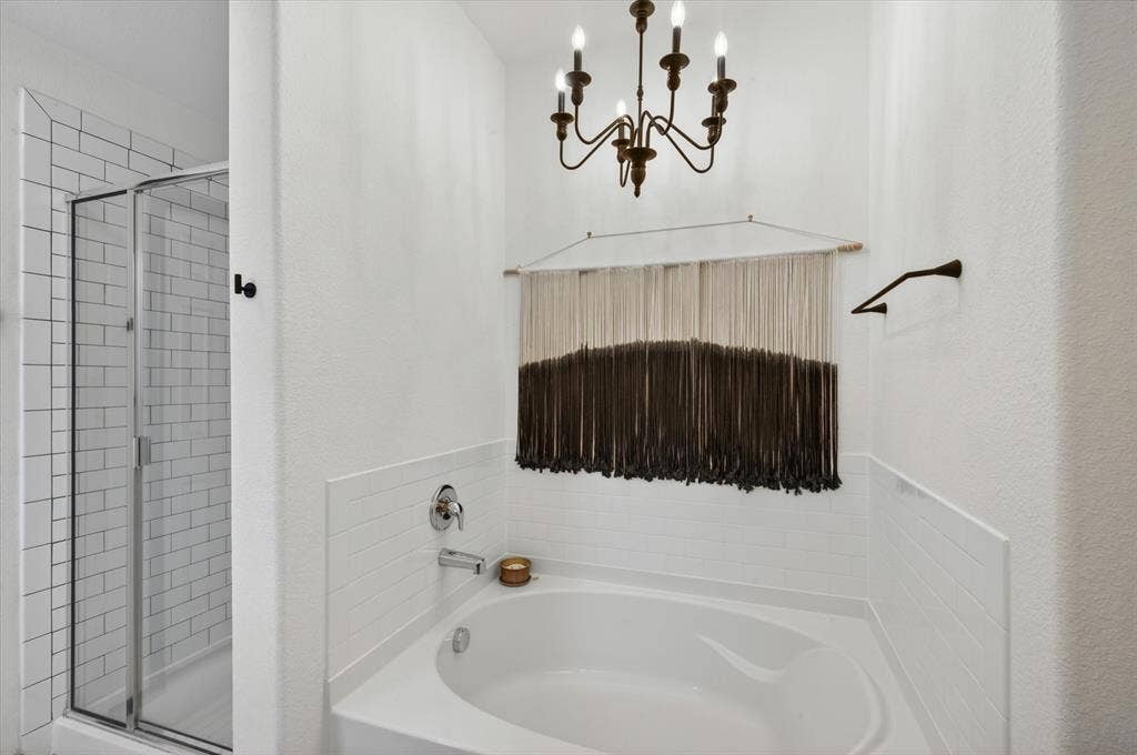 White bathroom featuring a built-in soaking tub, subway tile wainscoting, and an adjacent glass-enclosed shower with subway tile surround