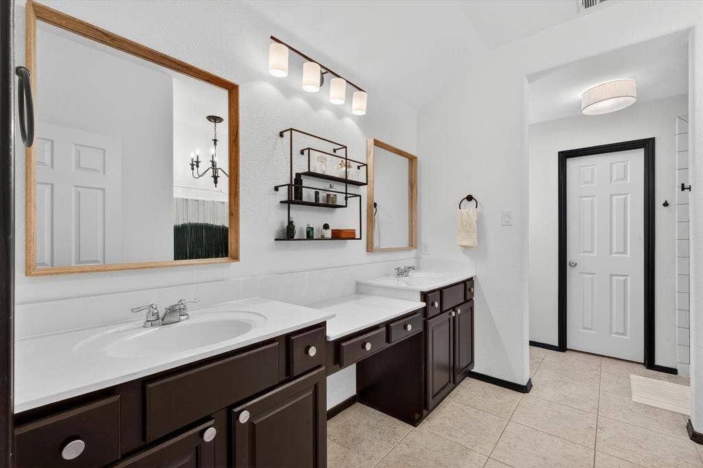 Spa-inspired primary bathroom featuring a dual-sink vanity with dark cabinetry, white countertop, and polished chrome fixtures