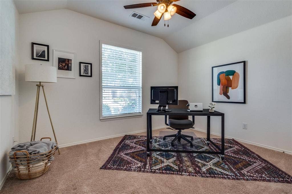 Vaulted ceiling, ceiling fan with integrated lighting, window with blinds, light tan carpeting
