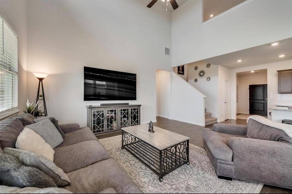 902 Western Way, Princeton, TX 75407 Living area featuring a soaring ceiling, wood-finish flooring, a contemporary staircase, an upper-level overlook, and recessed lighting