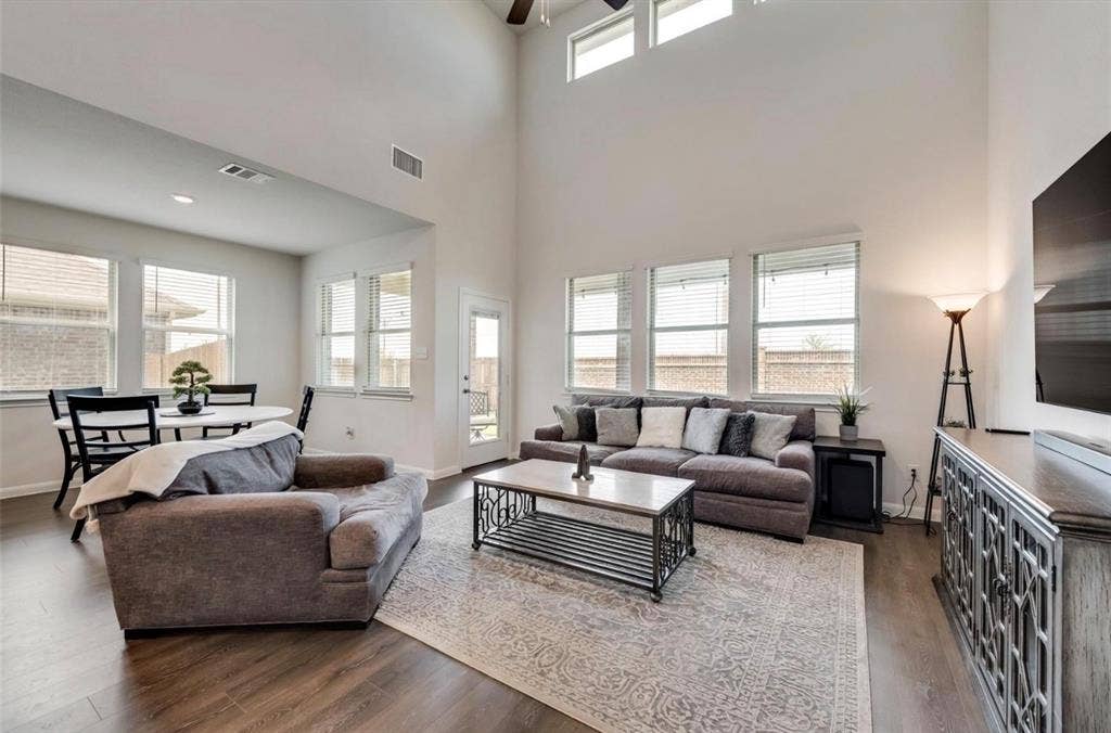 902 Western Way, Princeton, TX 75407 Two-story living area with high ceilings, upper transom windows, and wood-finish flooring