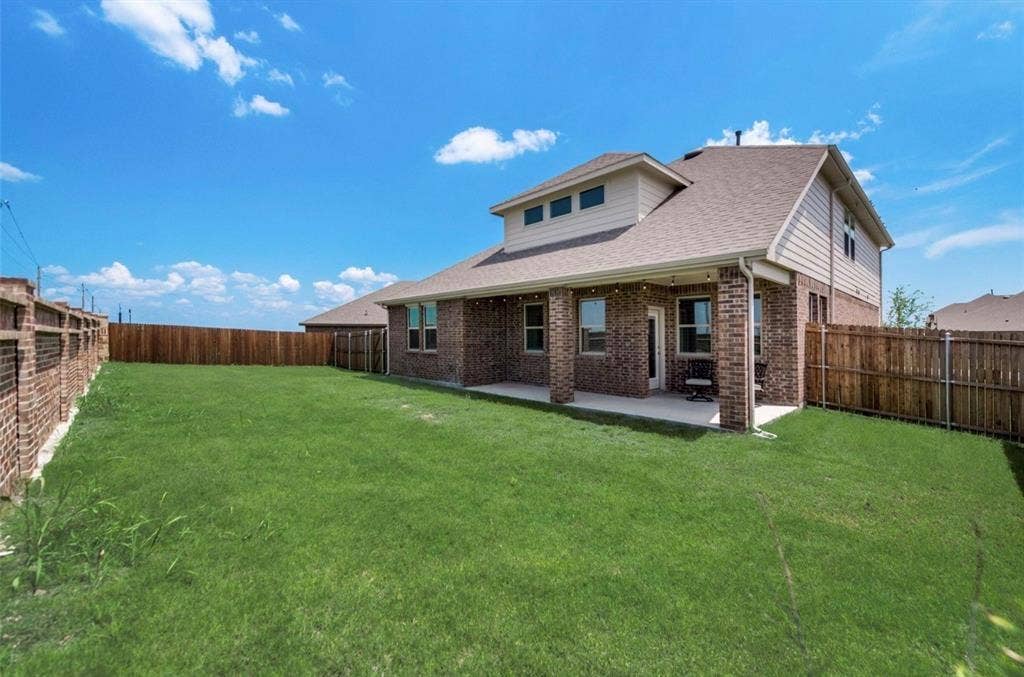 902 Western Way, Princeton, TX 75407 Expansive green lawn with a covered patio, brick columns, and a full privacy fence