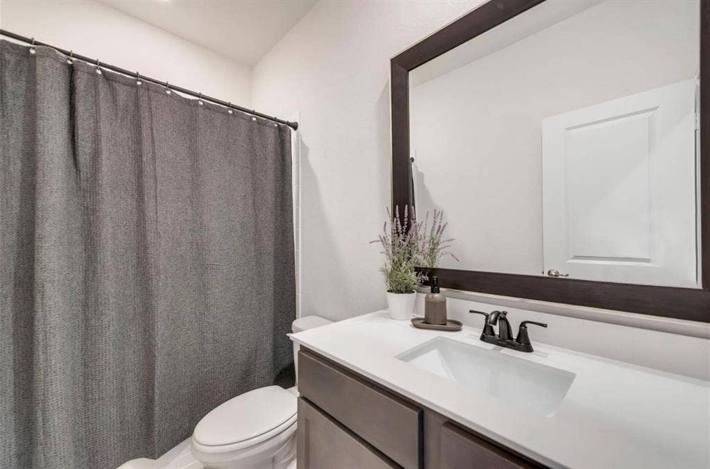 902 Western Way, Princeton, TX 75407 Modern bathroom featuring a white quartz countertop with an undermount sink, matte black faucet and hardware, and ample mirror with dark frame detailing