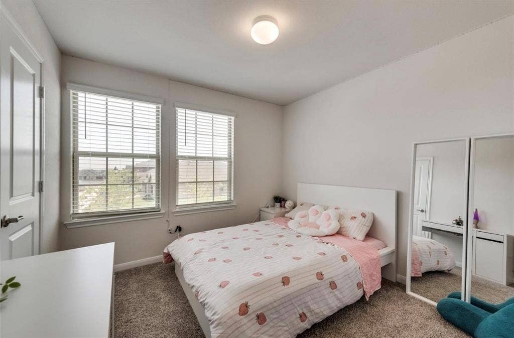 902 Western Way, Princeton, TX 75407 Bright secondary bedroom featuring dual windows with plantation shutters, carpeted flooring, and mirrored closet doors