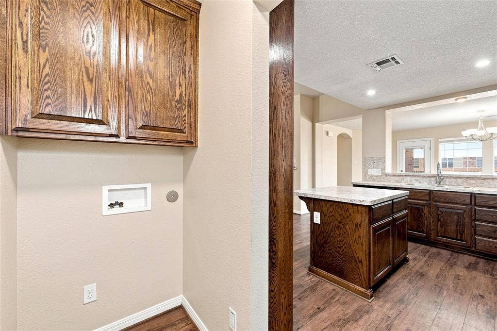204 Raven Ridge Court, Lacy Lakeview, TX 76705 Wood-finish flooring, dark wood cabinetry, light-toned countertops, and a built-in kitchen island