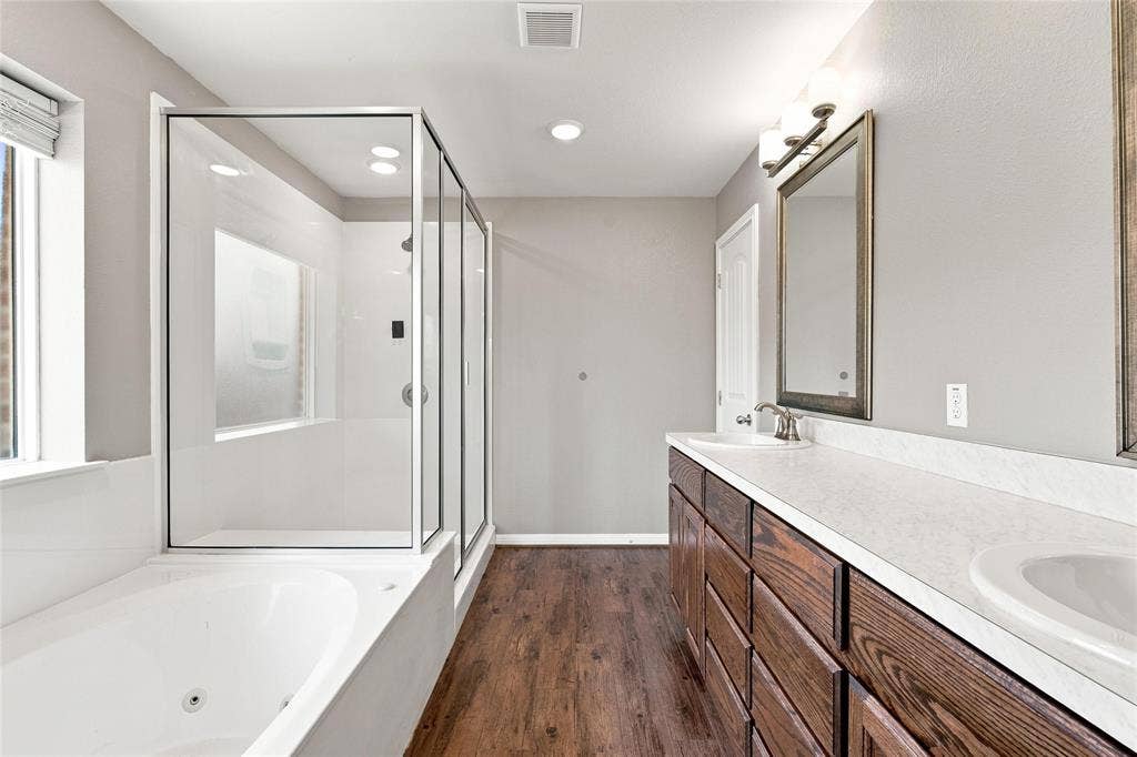 204 Raven Ridge Court, Lacy Lakeview, TX 76705 Dual vanity with integrated sinks, wood-finish cabinetry, frameless glass shower enclosure, built-in bathtub, and wood-finish flooring