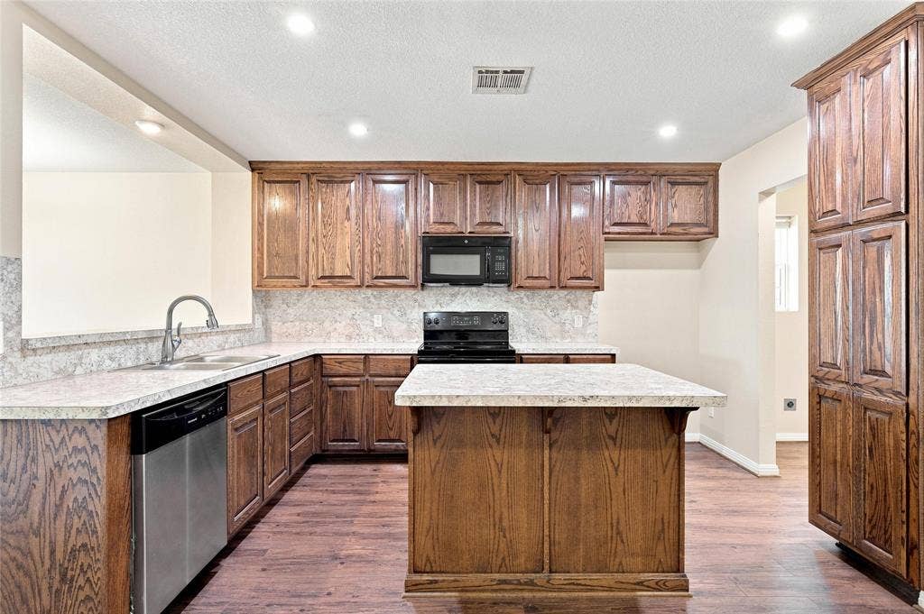 204 Raven Ridge Court, Lacy Lakeview, TX 76705 Kitchen featuring extensive wood cabinetry, L-shaped countertops, a kitchen island, integrated stainless steel dishwasher, and recessed lighting