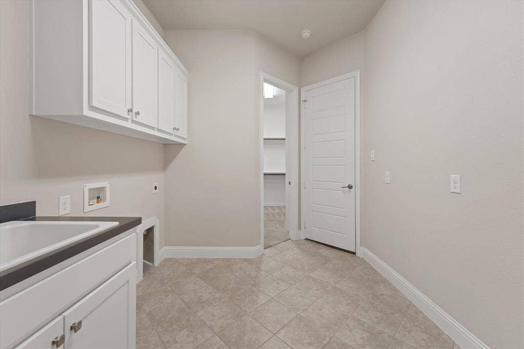 10846 Smoky Oak Trail, Argyle, TX 76226 laundry room features tons of space, full size hook ups, a sink, and storage cabinets. There is a Tesla charger in the one car garage off this room.