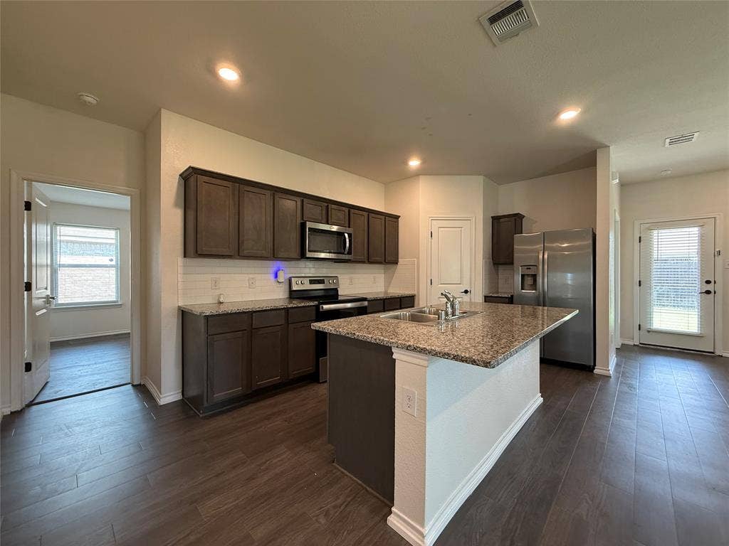 2702 Marotto Way, Seagoville, TX 75159 Kitchen featuring wood-finish flooring, dark wood cabinetry, and stainless steel appliances
