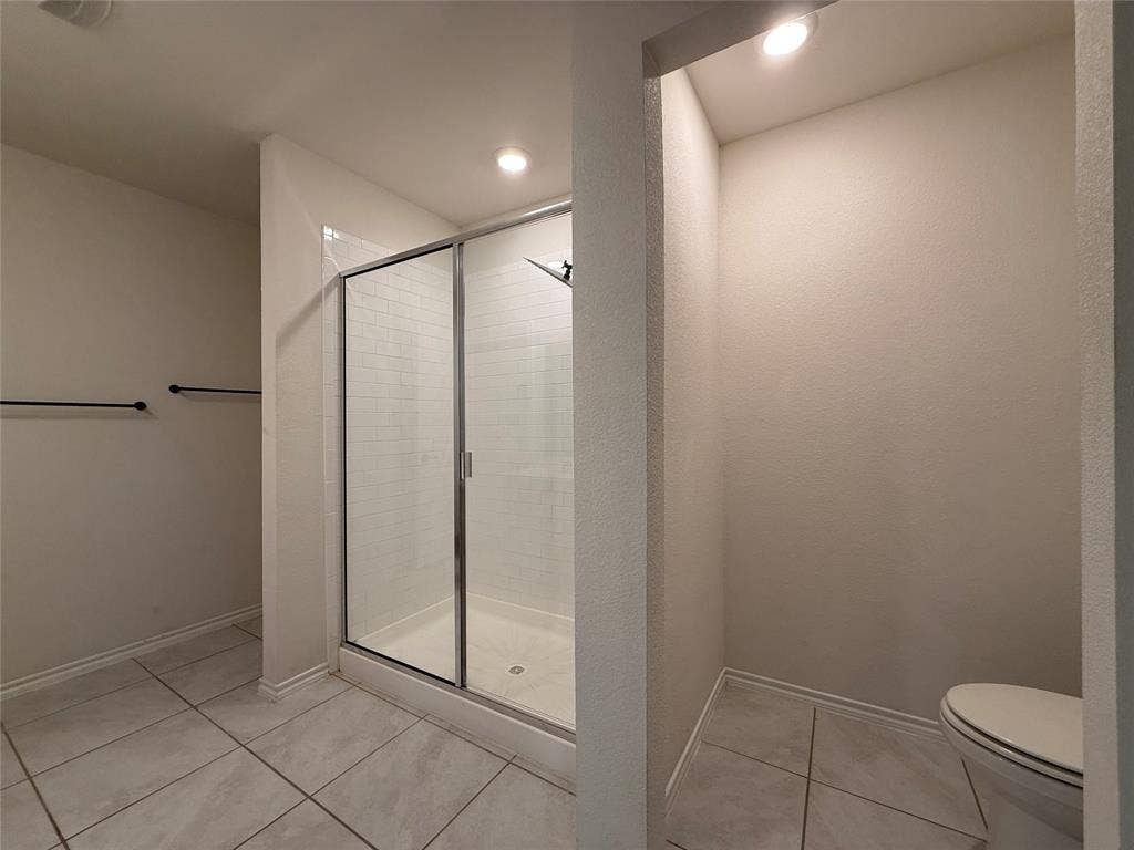 2702 Marotto Way, Seagoville, TX 75159 Bathroom featuring a glass-enclosed shower with subway tile surround, neutral-toned large format floor tiles, and recessed lighting
