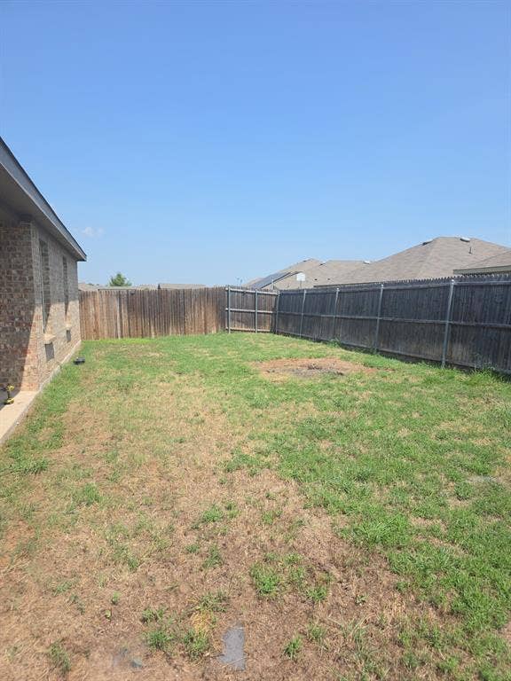 2702 Marotto Way, Seagoville, TX 75159 Expansive backyard space featuring a perimeter wood fence, partial brick exterior, and a large lawn area