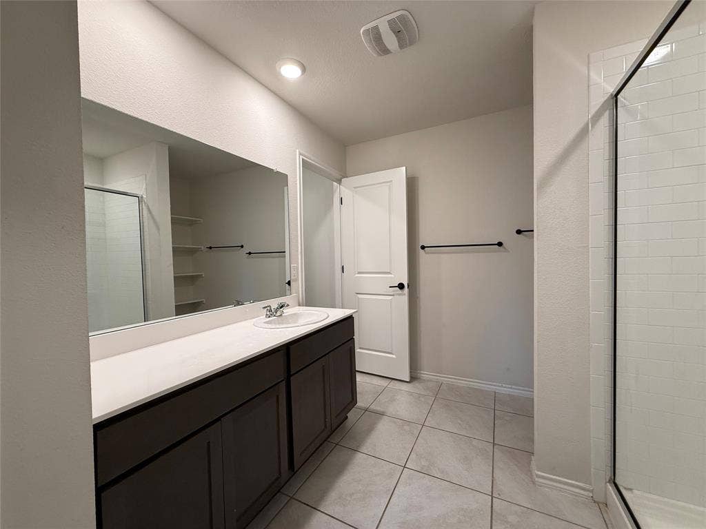 2702 Marotto Way, Seagoville, TX 75159 Bathroom featuring a single vanity with dark cabinetry, a white countertop, and a large wall-mounted mirror