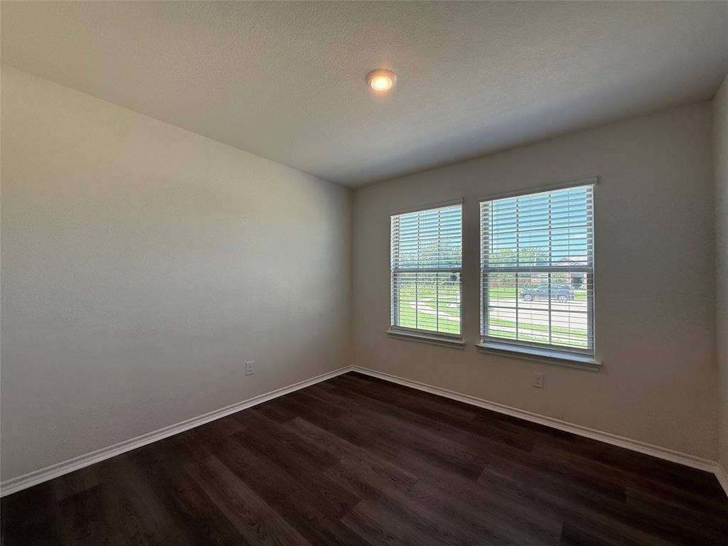 2702 Marotto Way, Seagoville, TX 75159 Room featuring wood-finish flooring, two large windows with blinds, light-toned wall paint, white trim, and a ceiling-mounted light fixture