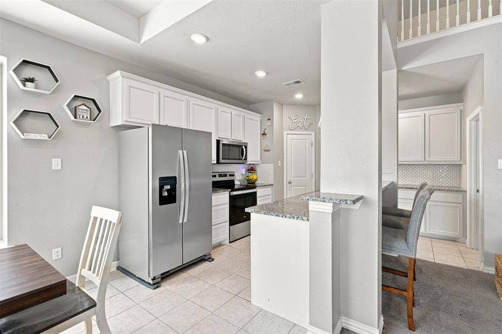 Kitchen featuring white cabinetry, stainless steel appliances, speckled countertops, and a subway tile backsplash
