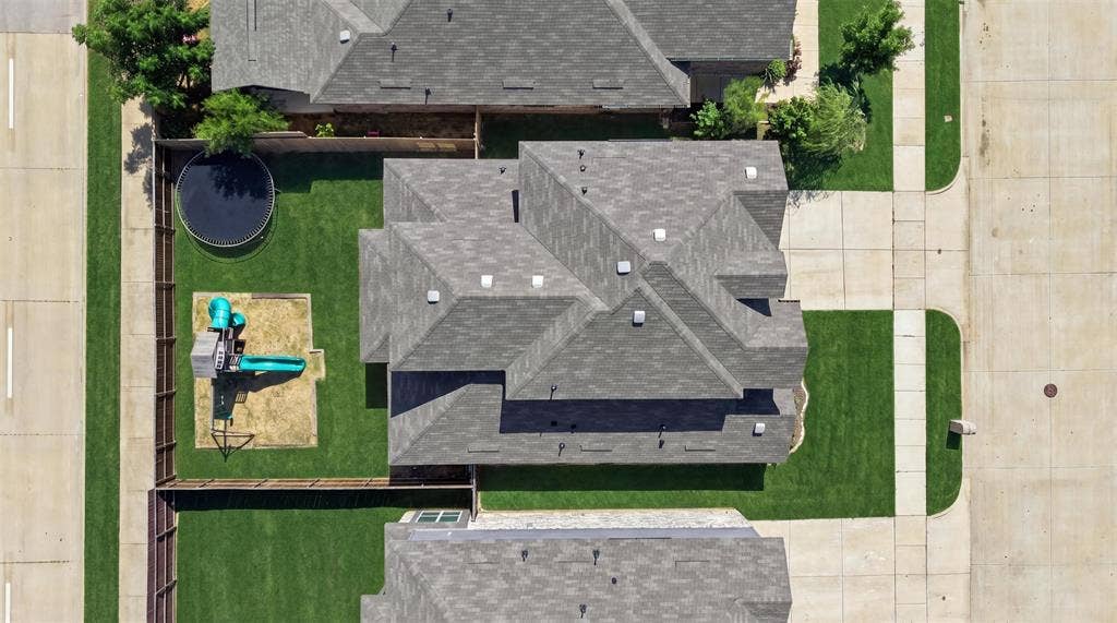 Aerial view highlighting the property's grey shingle roof and surrounding green lawns