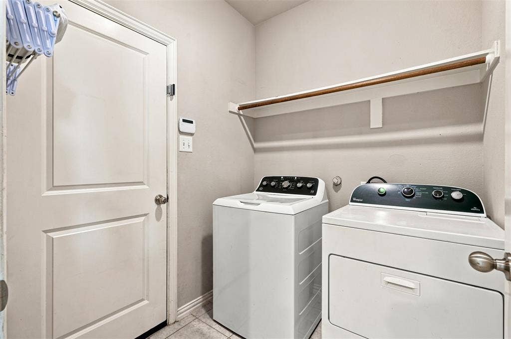 Dedicated laundry area featuring a white paneled door, light-toned walls, and a built-in shelving unit with a hanging rod