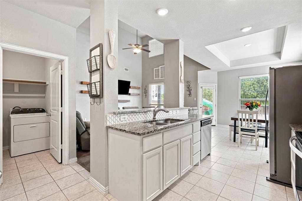 Kitchen featuring light gray cabinetry, granite countertops, and a white tile backsplash