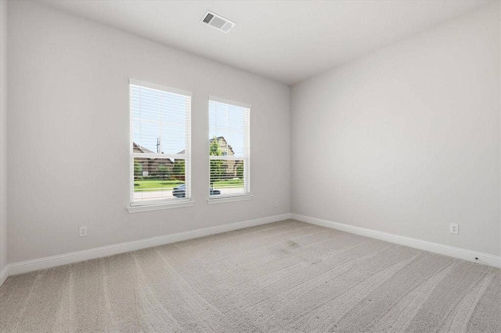 Carpeted room with neutral wall tones and white baseboards