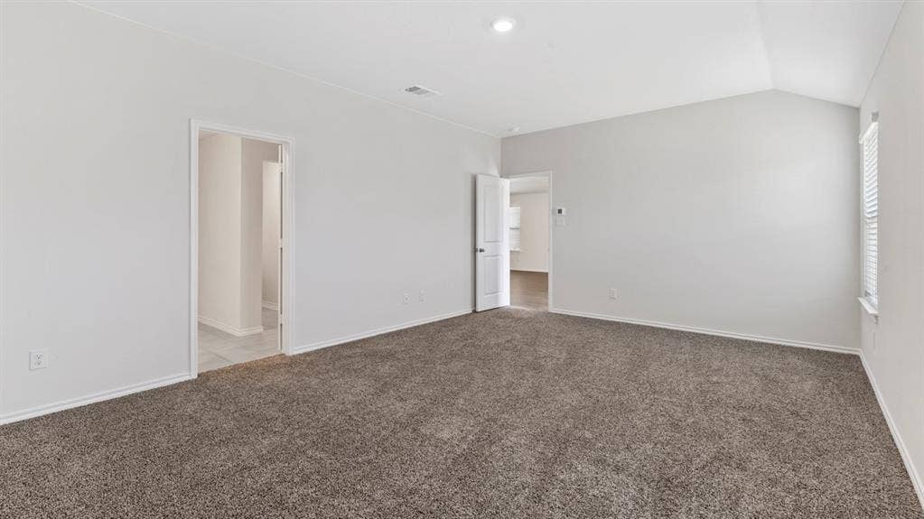 401 Banner Avenue, Royse City, TX 75189 Spacious room featuring vaulted ceilings, neutral-toned walls, and plush grey carpeting