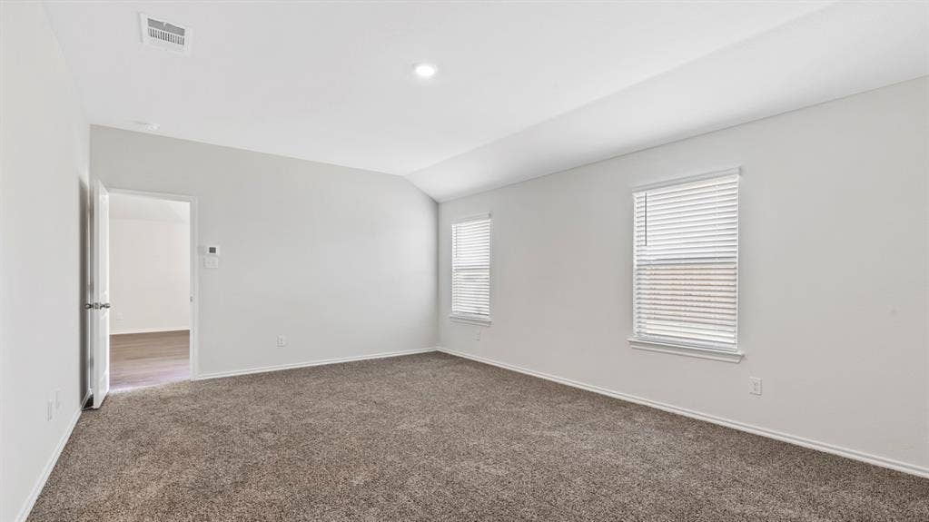401 Banner Avenue, Royse City, TX 75189 Spacious room featuring vaulted ceilings, neutral-toned carpeting, and two windows with blinds