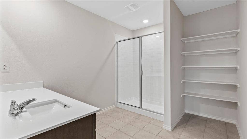 401 Banner Avenue, Royse City, TX 75189 Bathroom featuring a single vanity with an integrated sink, a glass-enclosed shower, and built-in shelving