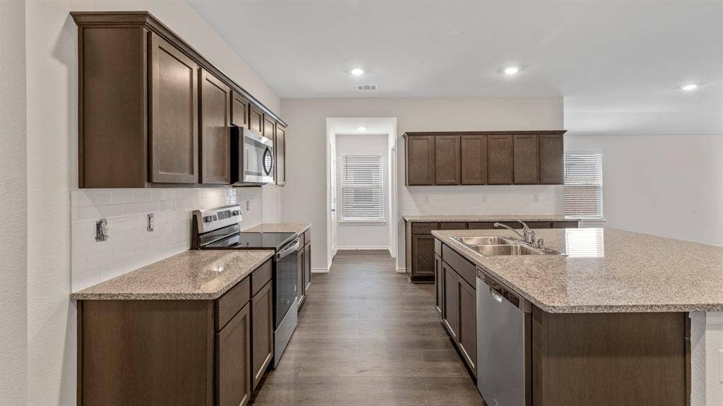 401 Banner Avenue, Royse City, TX 75189 Open-concept kitchen featuring dark wood cabinetry, granite countertops, and stainless steel appliances, including a range, microwave, and dishwasher