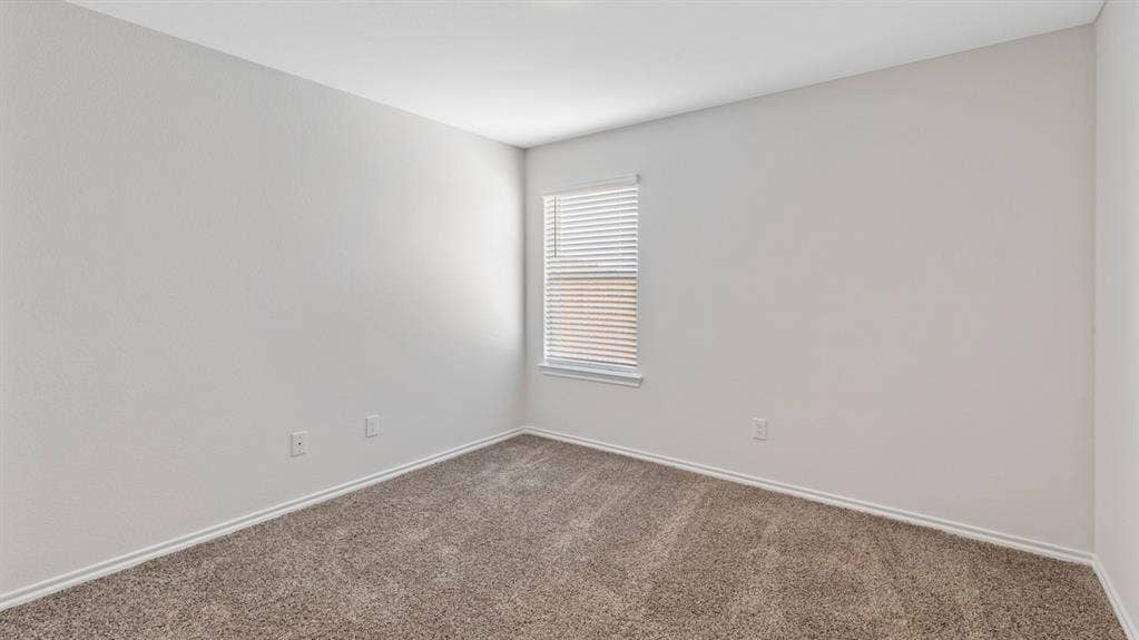 401 Banner Avenue, Royse City, TX 75189 Neutral-toned room featuring a single window with blinds, light gray textured walls, and a textured gray carpet