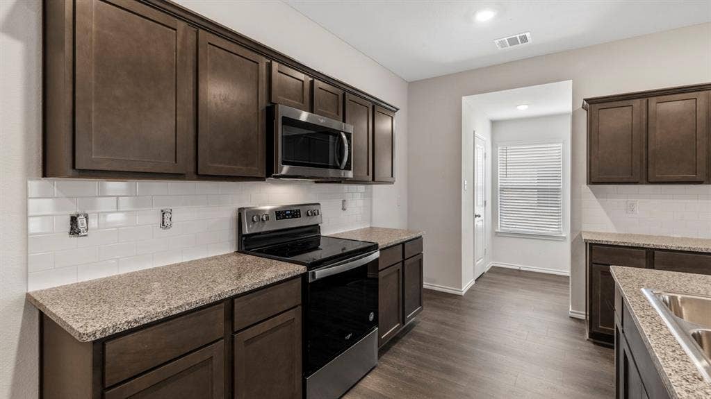 401 Banner Avenue, Royse City, TX 75189 Kitchen featuring dark wood-finish cabinetry, stainless steel appliances, granite-style countertops, white subway tile backsplash, and wood-finish flooring